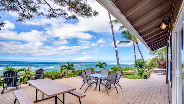 A wooden deck with a table and chairs, overlooking the ocean. - Beachfront | Sunsets | Spa | Surf Spot (Haleiwa)