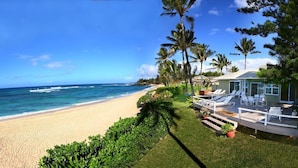A beachfront property with a sandy beach, palm trees, and a pool area with lounge chairs. - Beachfront | Sunsets | Spa | Surf Spot (Haleiwa)