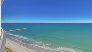 Ein Strand mit einem Steg, der sich ins Meer erstreckt, bewölkter Himmel und ruhige See.