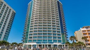 Ein mehrstöckiges Hotel mit geschwungener Fassade, Balkonen und einer Strandlage.