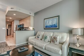 Un salon moderne avec un canapé en cuir blanc, une table basse et un tableau représentant des voiliers.