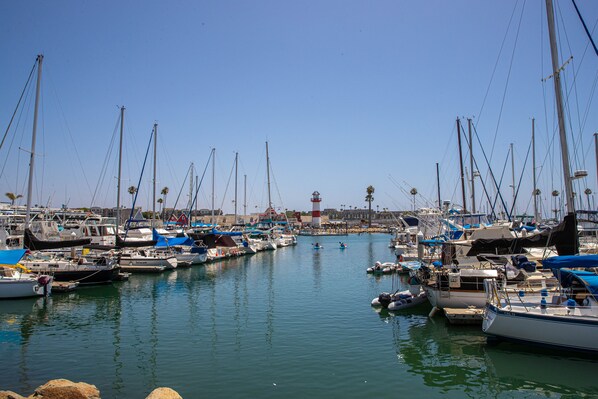 A marina with multiple boats docked, calm water, and a clear sky.