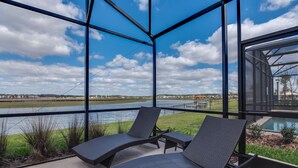 A balcony with two lounge chairs and a view of a river and distant landscape. - Private Pool Home w/Lake View! 10min Disney! *FREE WaterPark* (Kissimmee)