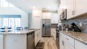 A modern kitchen with white cabinets, a stainless steel refrigerator, granite countertops, and a backsplash with a mosaic tile pattern. - Private Pool Home w/Lake View! 10min Disney! *FREE WaterPark* (Kissimmee)