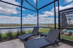 A balcony with two lounge chairs overlooking a river.