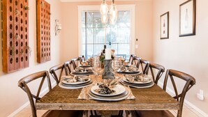 Comedor con una mesa de madera dispuesta para seis personas, rodeada de sillas de madera.