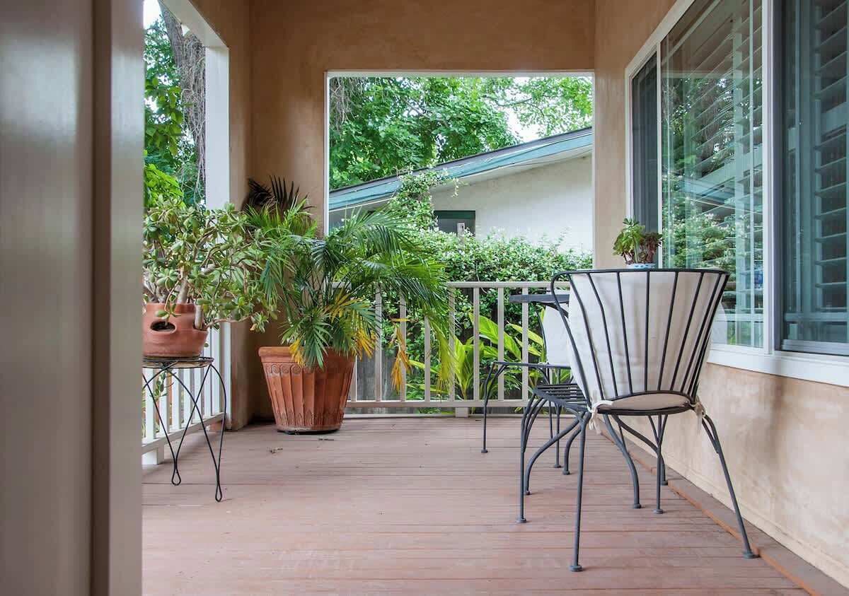 Una terraza de madera con macetas y una silla de metal.