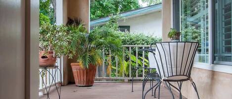 Una terraza de madera con macetas y una silla de metal.