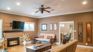Una sala de estar con chimenea, sofá, televisor y ventilador de techo.