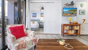 Una habitación con sofá, mesa de centro de madera, cama, escritorio y televisor.