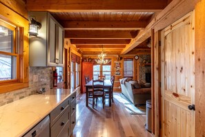 A wooden cabin interior with a dining area, kitchen, and living space.