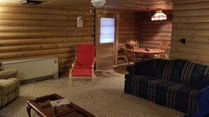 A cozy log cabin interior with a sofa, armchair, and a dining table with chairs. - LOG Cabin, 5 miles from town, but very country setting (Science Hill)