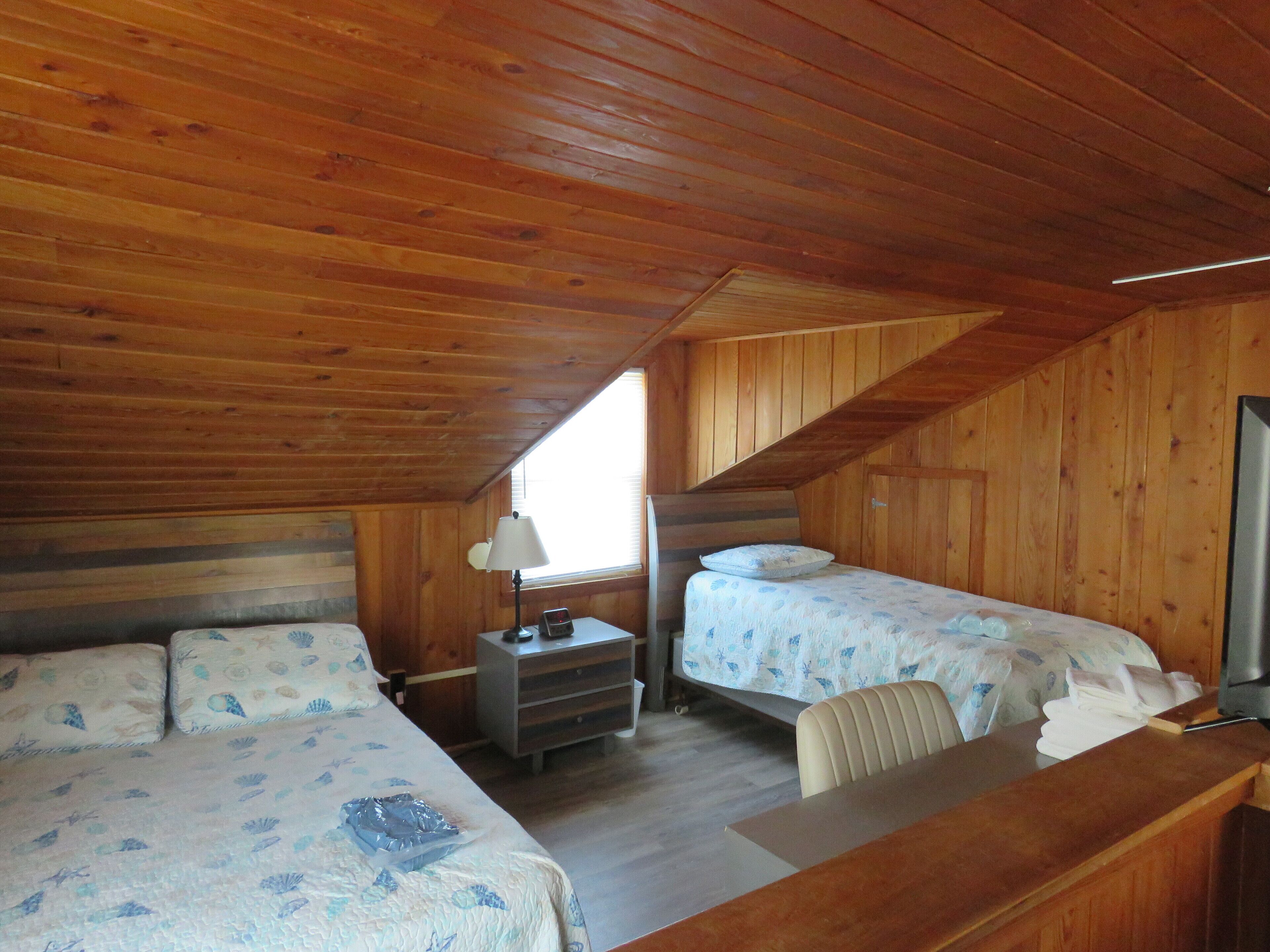 Een houten kamer met twee bedden, een bureau en een stoel.