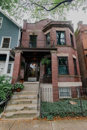 A two-story brick building with a front porch, steps, and a metal fence. - Great Location-Beautiful Friendly Andersonville Neighborhood (Chicago)