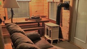 Interior acogedor de una cabaña de troncos con un sofá, una mesa, una lámpara y un estufa de leña.