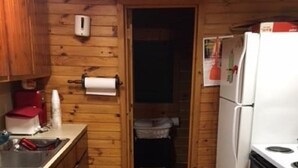 Una cocina compacta con paredes de madera, un refrigerador, un lavavajillas y una pequeña encimera.