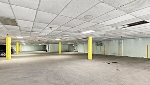 A parking garage with concrete floors, yellow pillars, and a grid ceiling.