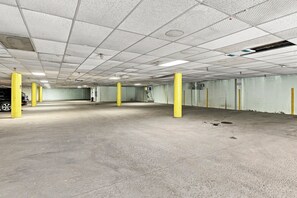 Un parking avec des planchers en béton, des piliers jaunes et un plafond à structure grillagée.