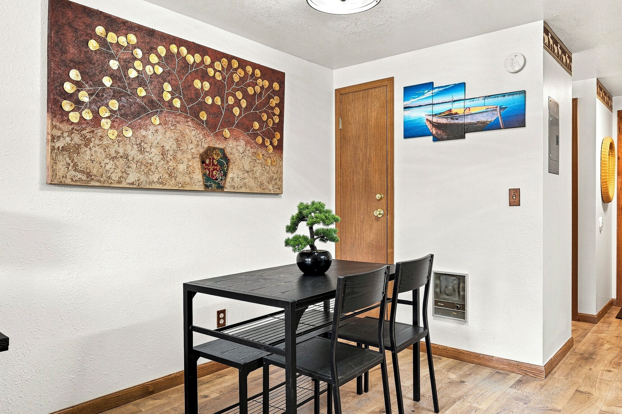 A dining area with a table and chairs, a potted plant, and artwork on the walls.