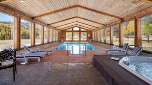 A covered swimming pool area with lounge chairs and a hot tub.