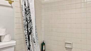 A bathroom with a bathtub, toilet, and shower curtain.