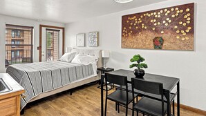 A bedroom with a bed, bedside table, lamp, and a painting on the wall.