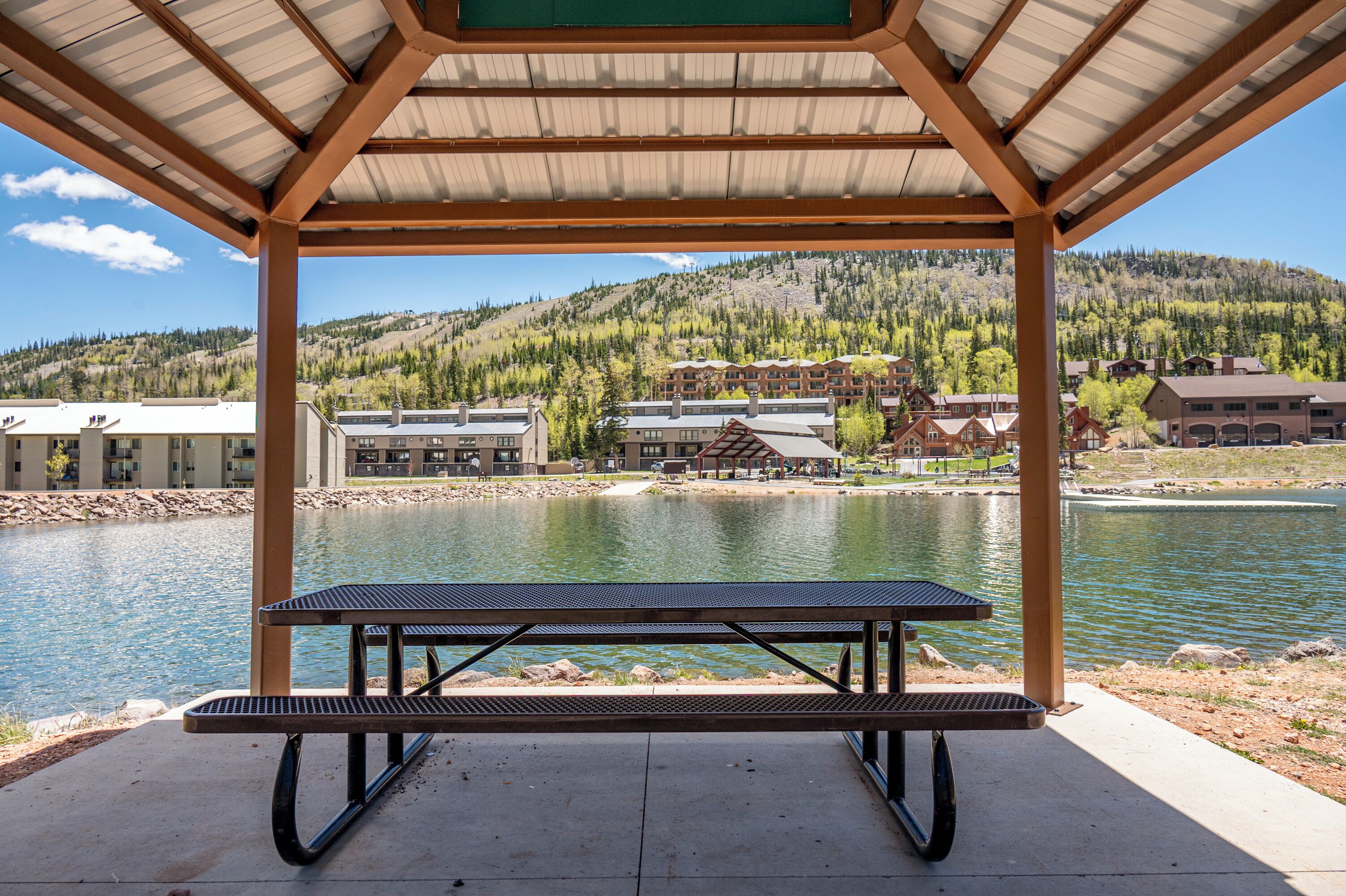 A covered picnic area with a view of a lake and buildings in the background.