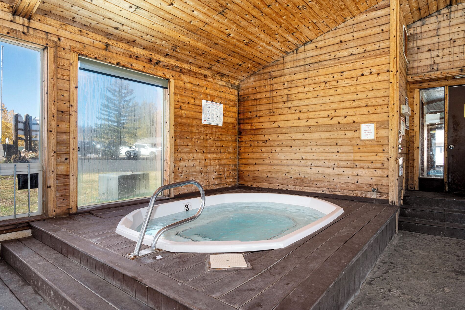 A wooden cabin with a hot tub and a glass door leading outside.