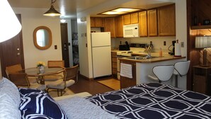 Cocina funcional con armarios de madera, refrigerador y microondas. Cuenta con una mesa de comedor con sillas y una pequeña isla con pileta.