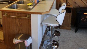 Una cocina con armarios de madera, un fregadero de acero inoxidable y una encimera blanca.