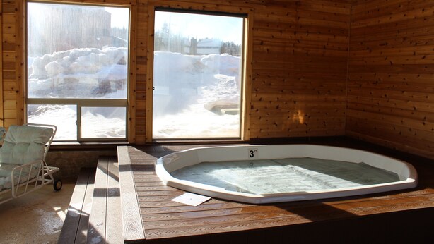 Una cabaña de madera con un jacuzzi y una banca junto a una ventana.