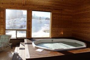 Una cabaña de madera con un jacuzzi y una banca junto a una ventana.