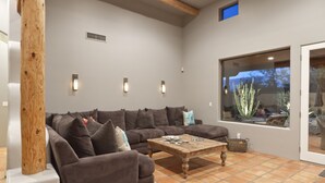 Una sala de estar con un amplio sofá modular, una mesa de centro de madera y un ventanal con vistas a cactus.