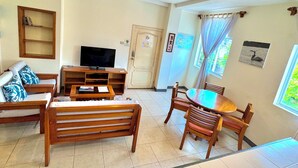 A living room with a TV, sofa, coffee table, and dining area with chairs. - This two-bedroom is a perfect island getaway. (Puerto Ayora, Santa Cruz Island)