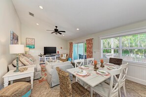 A living room with a TV, sofa, and dining table set for a meal.