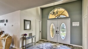 A foyer with a white door, a console table with a vase, and a mirror on the wall. - Beautiful 3 bed 2 bath, Heated Pool, Minutes from the Ocean (Sebastian)