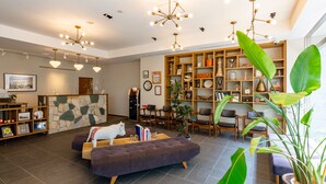 A modern living area with a sofa, a cat, a bookshelf, and a reception desk. - The OneFive Tokyo Shibuya (Tokyo)