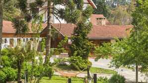 Un jardín exuberante con una hamaca, un sendero y un edificio con tejado de tejas rojas.