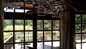 Una habitación con ventanas amplias, una mesa de madera y copas colgantes.