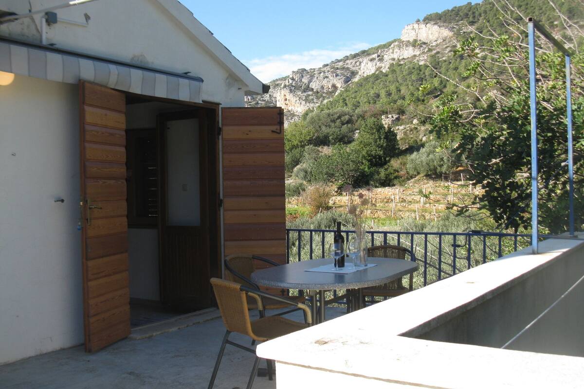 Un balcon avec une table et des chaises, donnant sur un paysage montagneux.