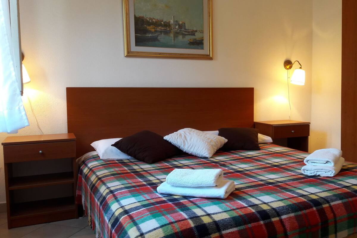 Une chambre d’hôtel avec un lit, une table de chevet, une armoire et un tableau au mur.