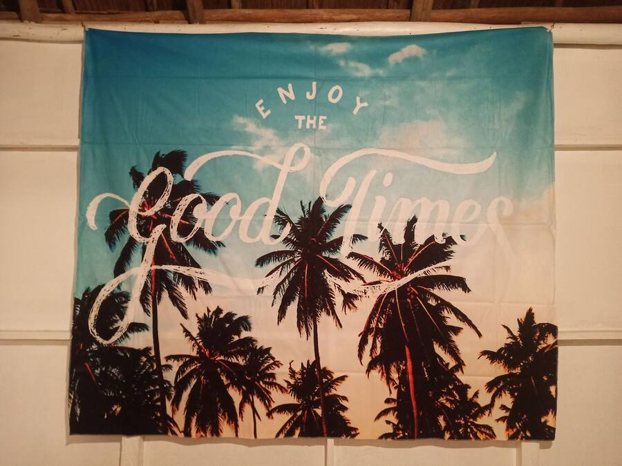 A wall hanging with palm trees and the text "ENJOY THE Good Times".