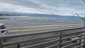 A coastal view from a balcony with a railing, a car parked on the street, and a cloudy sky. - A.S.J. Backpackers Baler (Baler)