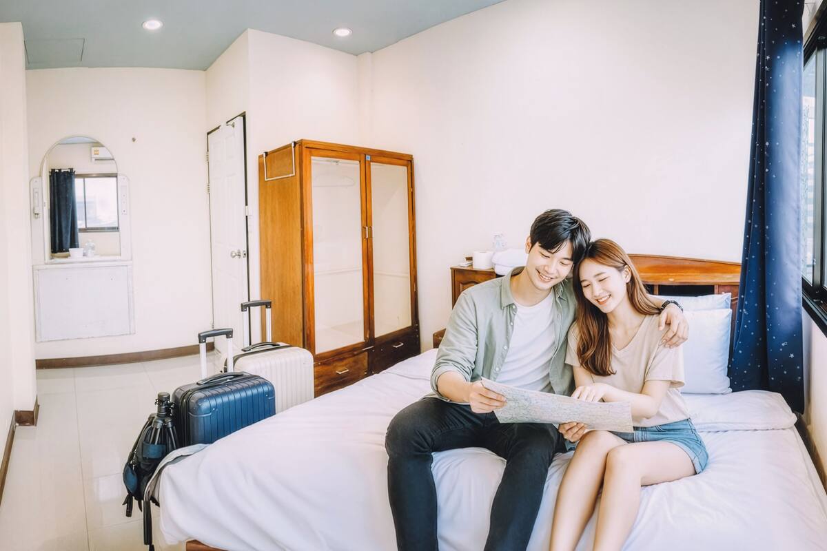 Een hotelkamer met een bed, een kledingkast, een spiegel en een raam.