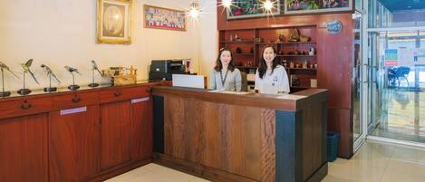 A reception desk with wooden panels, a television, and a wall with framed artwork.