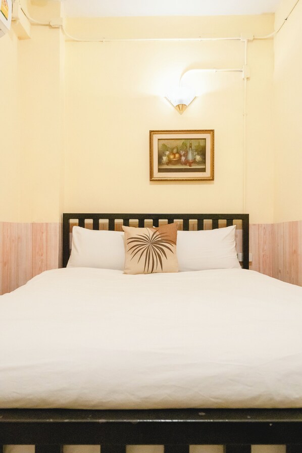 A bed with white bedding, a wooden headboard, and a single decorative pillow. - Khaosan Station Hostel (Bangkok)