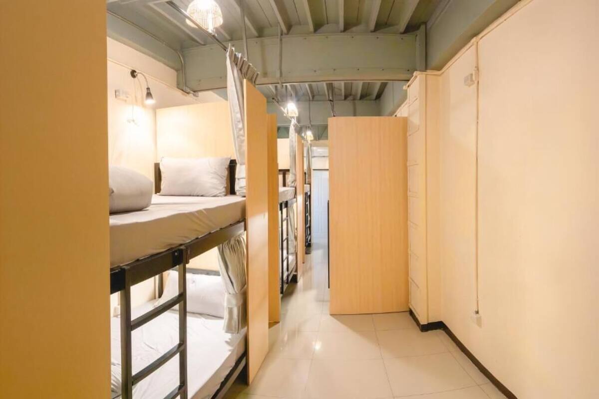 Een gang met stapelbedden, een houten garderobe en een betegelde vloer.