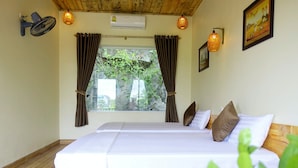 Een slaapkamer met een bed, gordijnen, een airconditioning en een raam met uitzicht op groen.