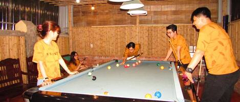 A billiards table labeled "CT6 SPECIAL BILLIARDS" in a room with wooden walls and ceiling, featuring hanging lights and a bamboo backdrop.