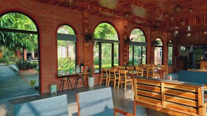 Een restaurant met bakstenen muren, grote gewelfde ramen en houten meubels.
